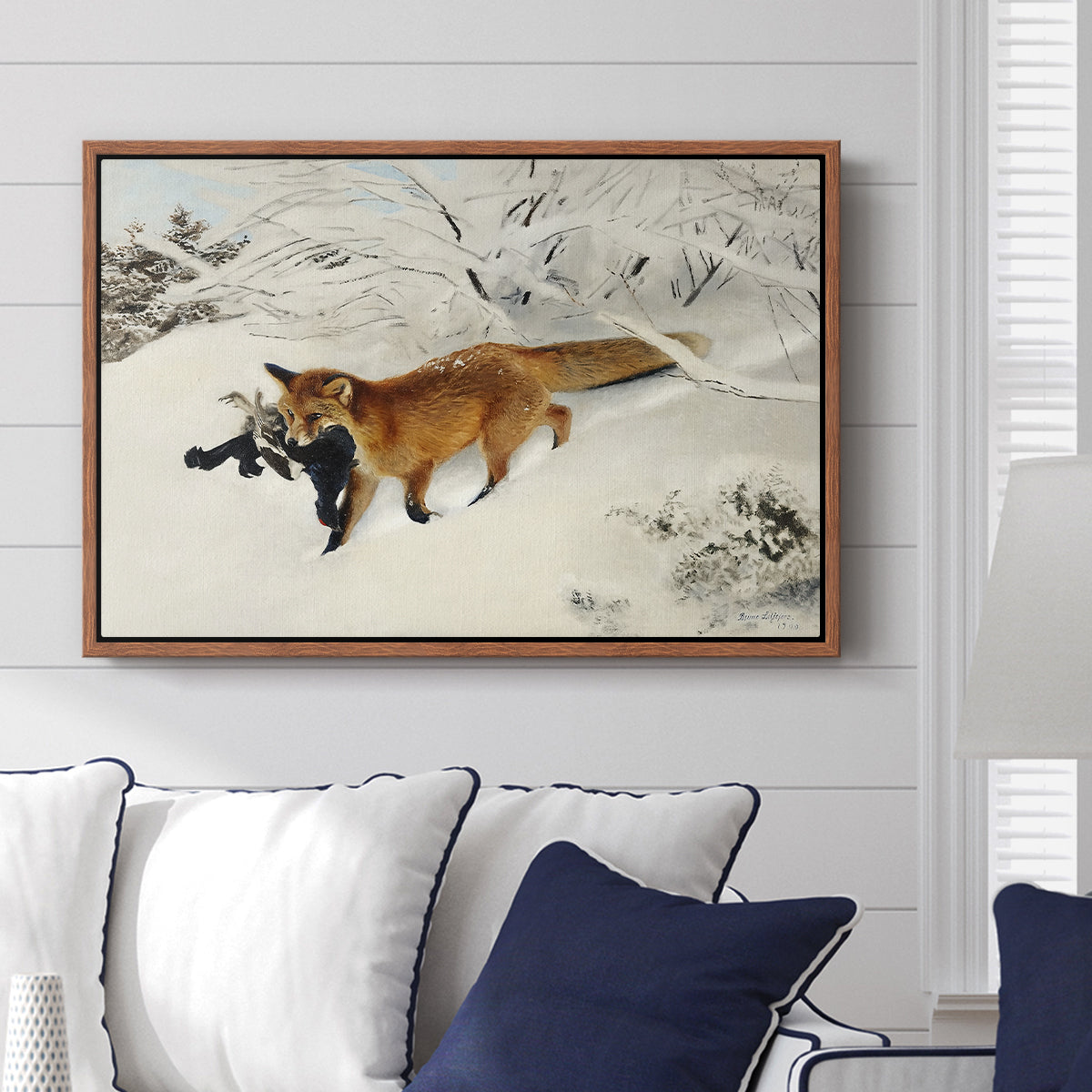 Fox in Snow Landscape, 1900 by Bruno Liljefors displayed above a sofa in a living room in a walnut floater frame, featuring a wildlife scene of fox moving swiftly through winter terrain.
