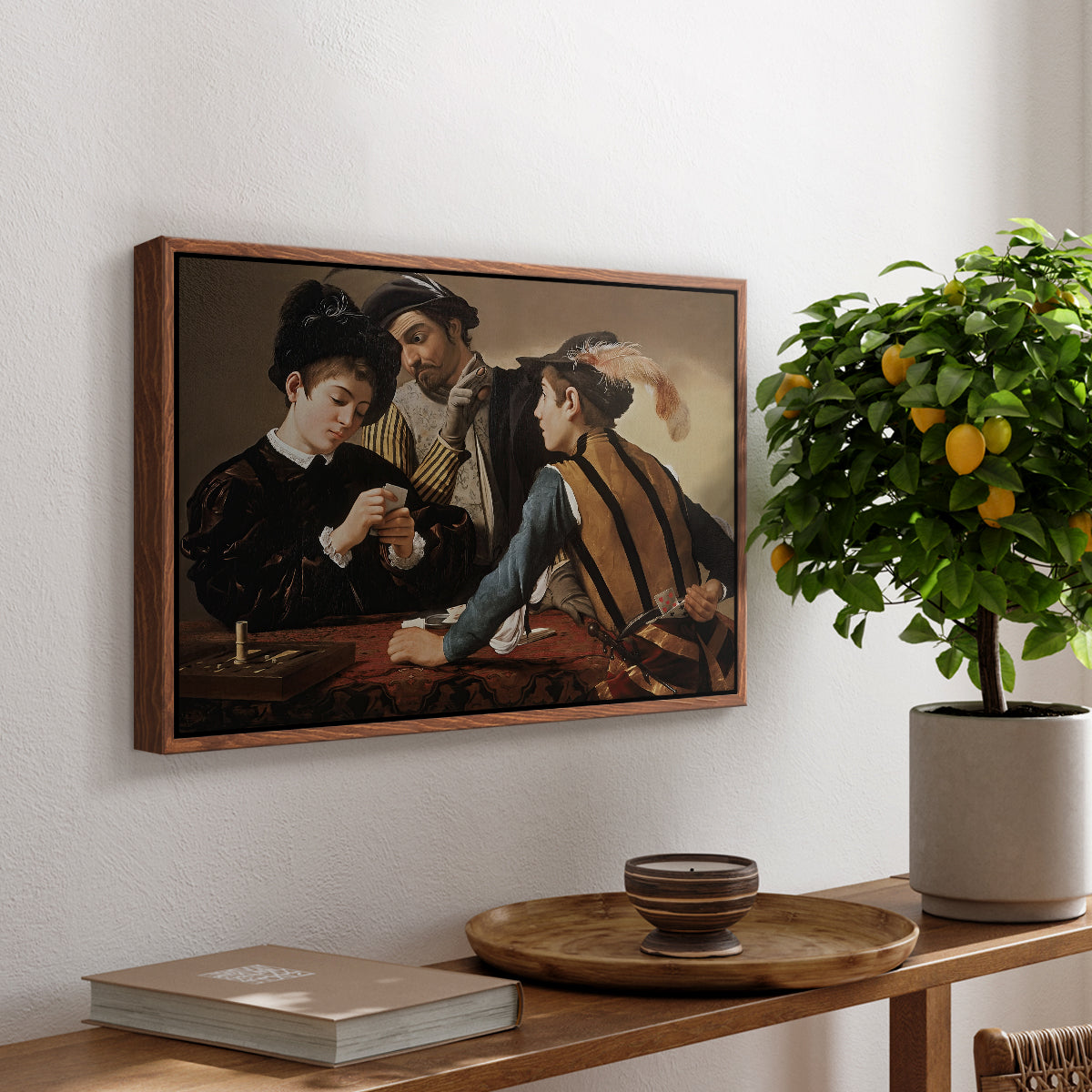 The Cardsharps, c. 1594 by Caravaggio, presented in a walnut floater framed canvas featuring two men cheating at cards while a third figure secretly observes behind them, displayed above a hallway console table.