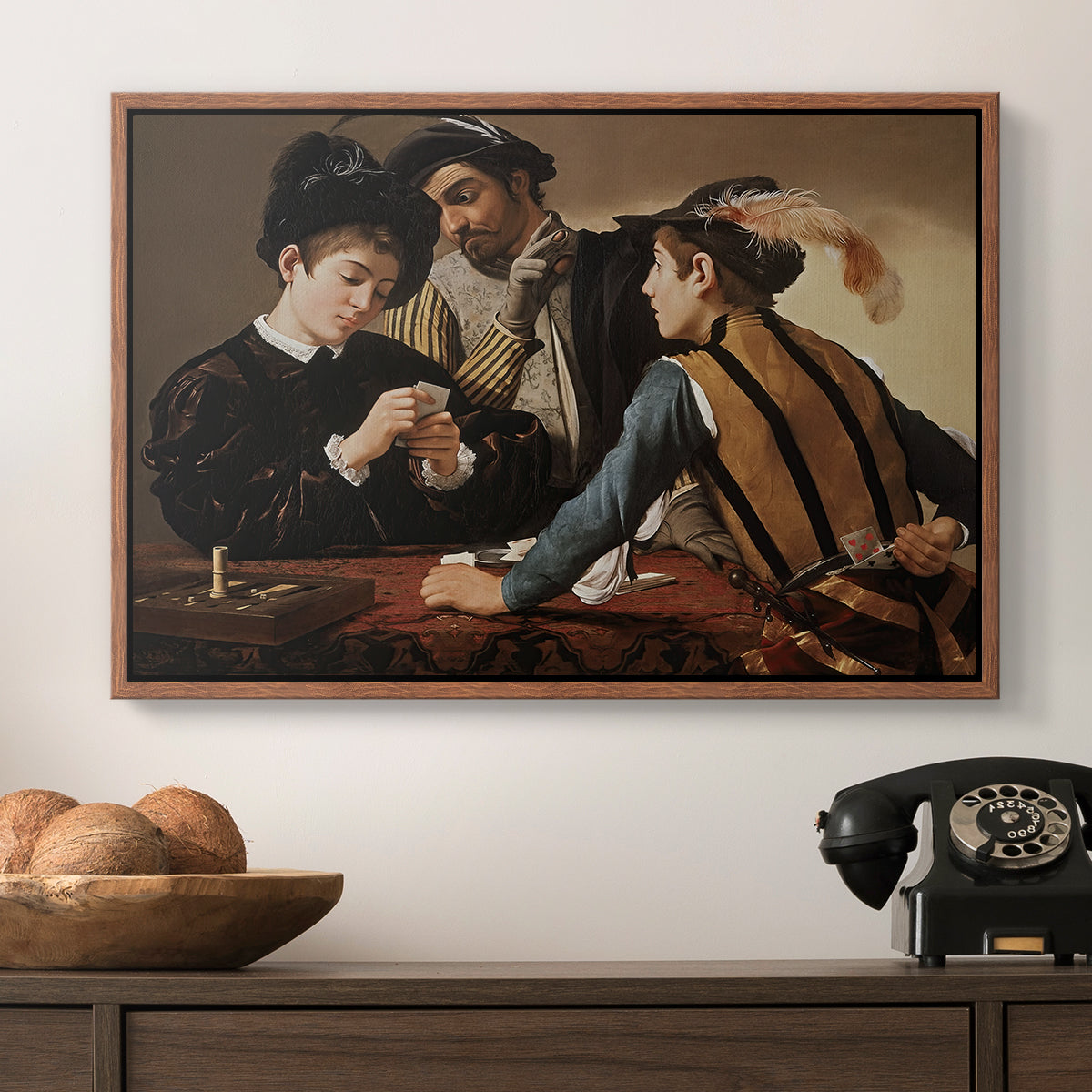 The Cardsharps, c. 1594 by Caravaggio in a walnut floater framed canvas displayed above a console table in a hallway, featuring a dramatic interior scene of gambling and trickery among figures.