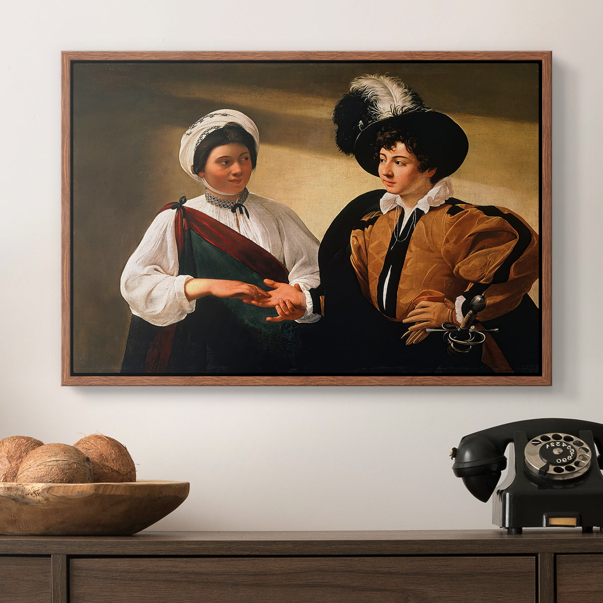 The Fortune Teller (Louvre Version), c. 1595 by Caravaggio in a walnut floater framed canvas displayed above a console table in a hallway, featuring two figures engaged in fortune telling with hidden deception.