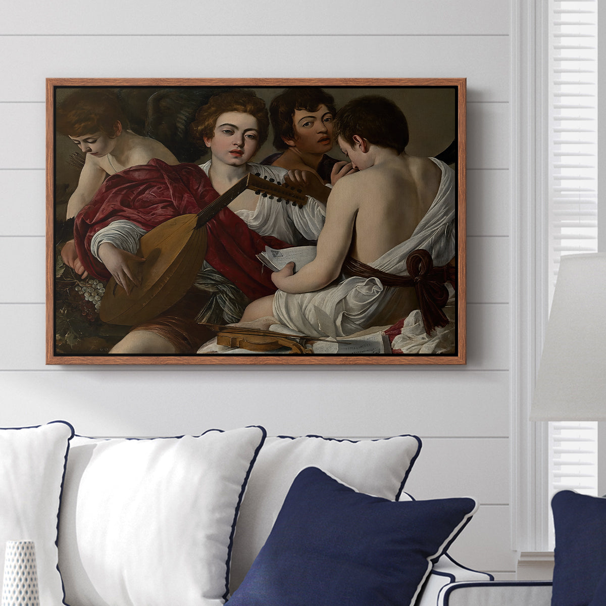The Musicians, c. 1595 by Caravaggio displayed above a sofa in a living room in a walnut floater frame, featuring an ensemble of musicians holding lute and singing in close arrangement.