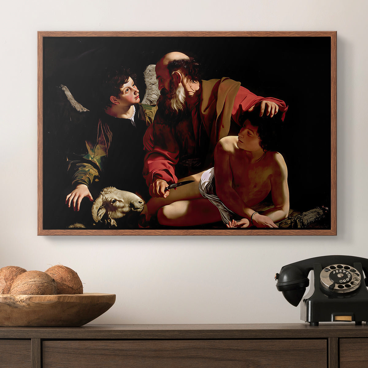 The Sacrifice of Isaac (Uffizi Version), c. 1603 by Caravaggio in a walnut floater framed canvas displayed above a console table in a hallway, featuring an intense religious narrative with figures in close physical struggle.