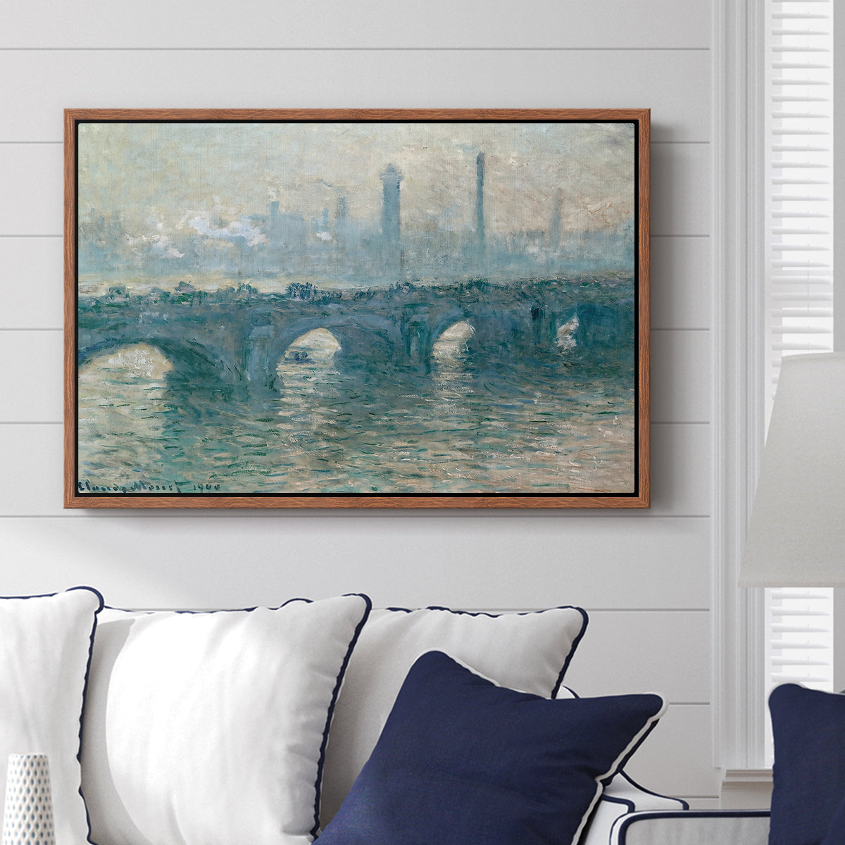 Waterloo Bridge, Gray Weather, 1900 by Claude Monet displayed above a sofa in a living room in a walnut floater frame, featuring an impressionist cityscape with bridge fading into fog over water.