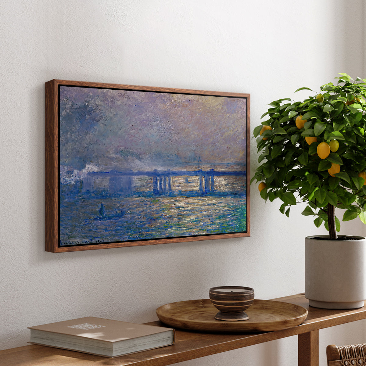 Charing Cross Bridge, 1903 by Claude Monet, presented in a walnut floater framed canvas featuring an impressionist view of bridge stretching across river with soft light and haze, displayed above a hallway console table.