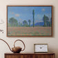Walnut floater framed canvas featuring a vibrant meadow scene with flowers and vertical tree forms, displayed above a cabinet in a soft-toned living room.