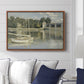 The Bridge at Argenteuil, 1874 by Claude Monet displayed above a sofa in a living room in a walnut floater frame, featuring an impressionist river scene with boats passing beneath bridge.