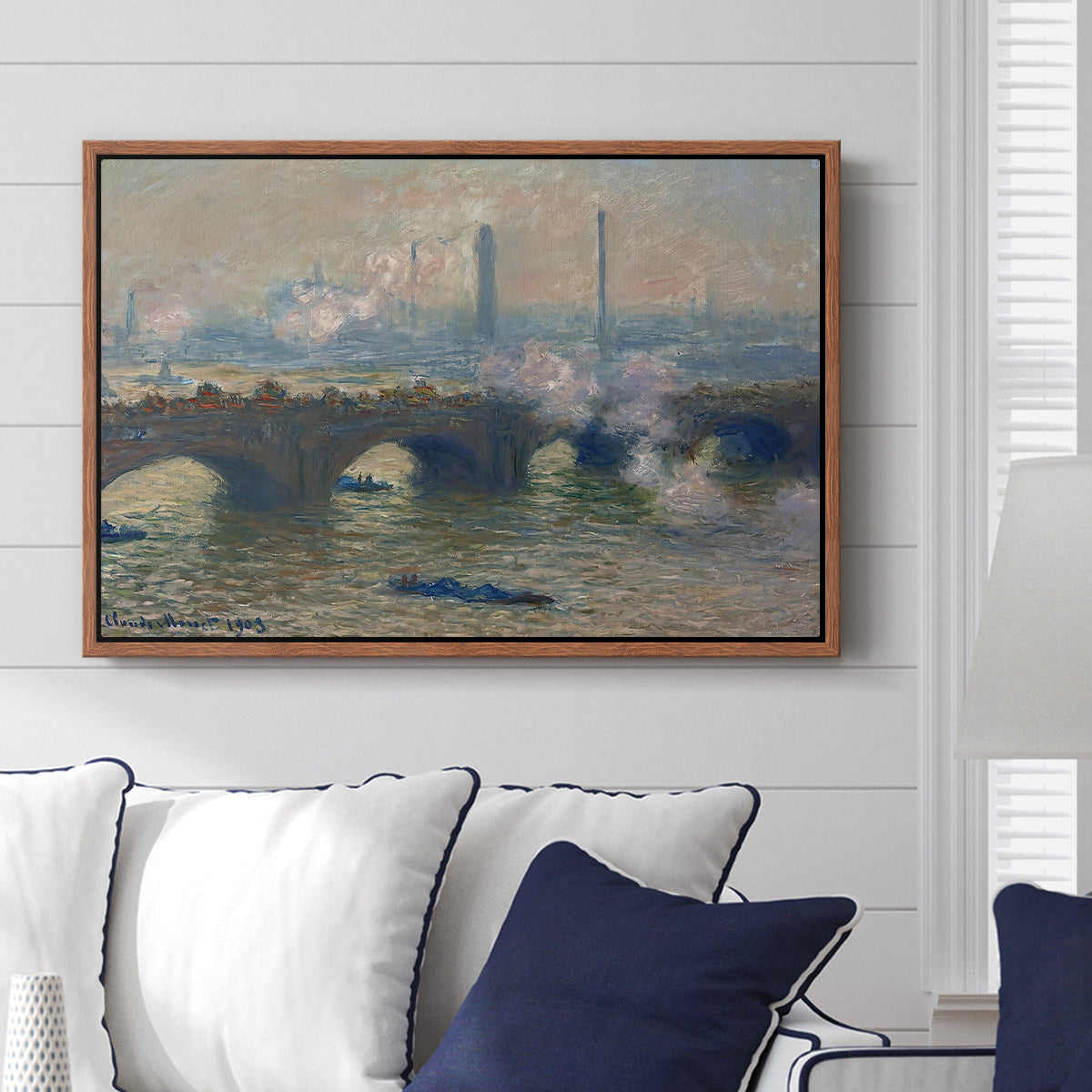 Waterloo Bridge, Gray Day, 1903 by Claude Monet displayed above a sofa in a living room in a walnut floater frame, featuring an impressionist depiction of bridge with soft gray tones and haze.