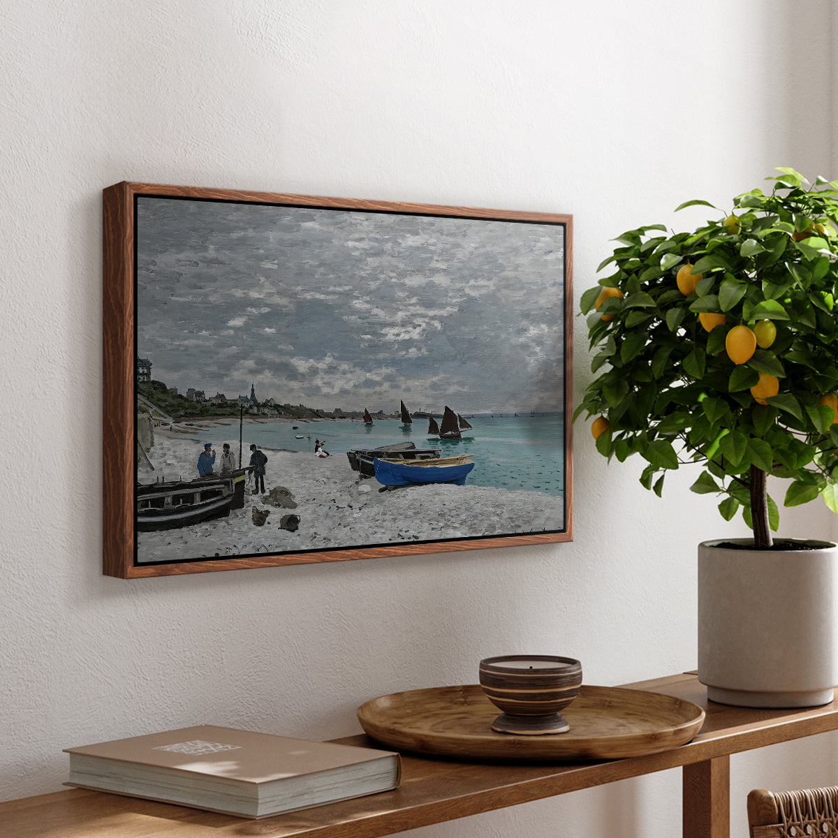 The Beach at Sainte-Adresse, 1867 by Claude Monet, presented in a walnut floater framed canvas featuring a seaside promenade with figures, flags, and boats along the coast, displayed above a hallway console table.