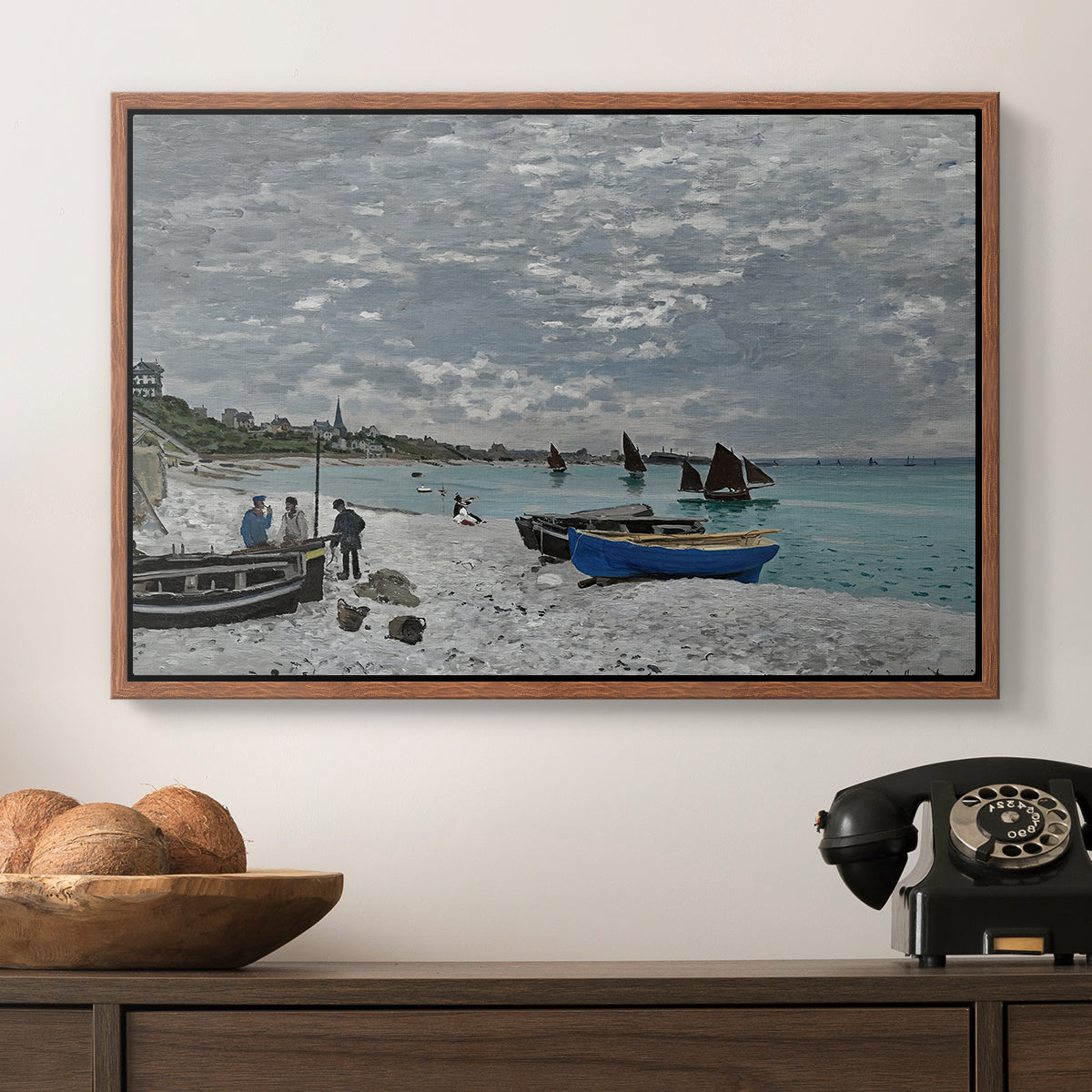 The Beach at Sainte-Adresse, 1867 by Claude Monet in a walnut floater framed canvas displayed above a console table in a hallway, featuring an impressionist seaside gathering with flags and ocean view.