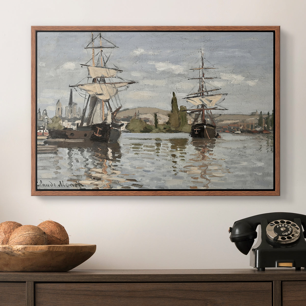 Ships Riding on the Seine at Rouen, 1872 by Claude Monet in a walnut floater framed canvas displayed above a console table in a hallway, featuring a nautical landscape with vessels resting on calm water.