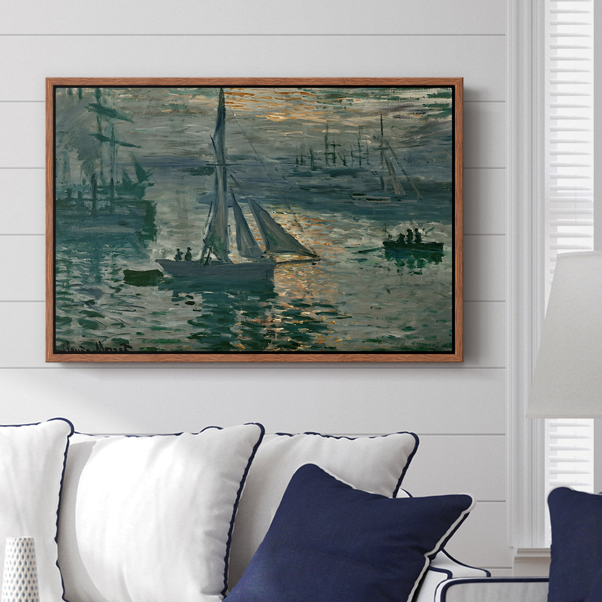 Sunrise (Marine), 1873 by Claude Monet displayed above a sofa in a living room in a walnut floater frame, featuring an impressionist seascape with glowing sun and misty water.