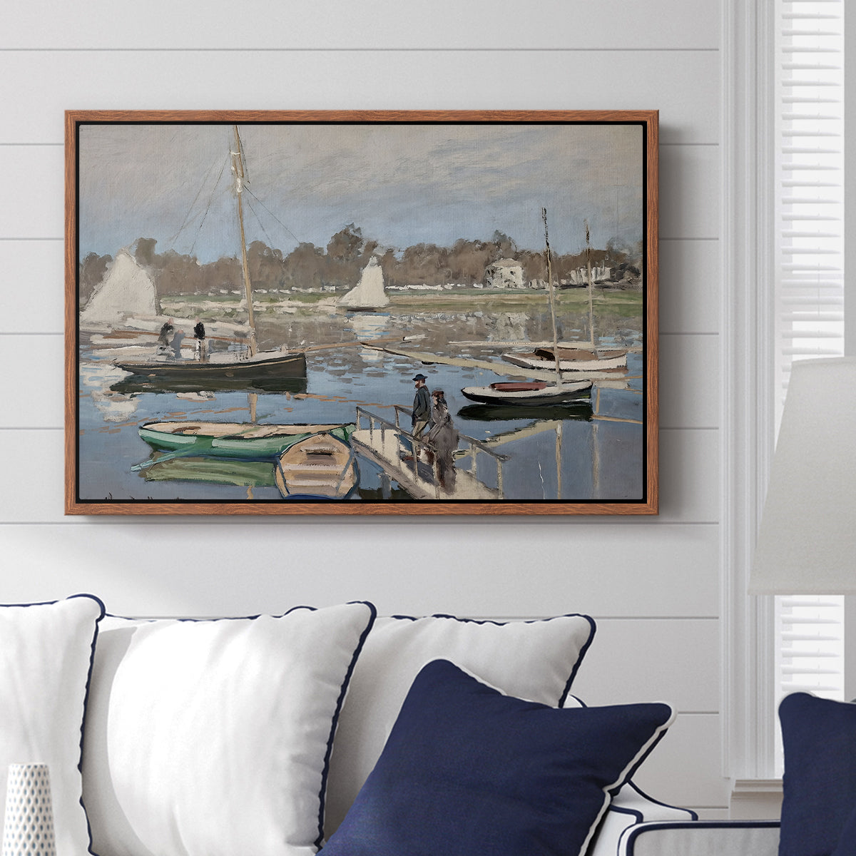 The Basin at Argenteuil, 1874 by Claude Monet displayed above a sofa in a living room in a walnut floater frame, featuring an impressionist boating scene with clustered masts and gentle ripples.
