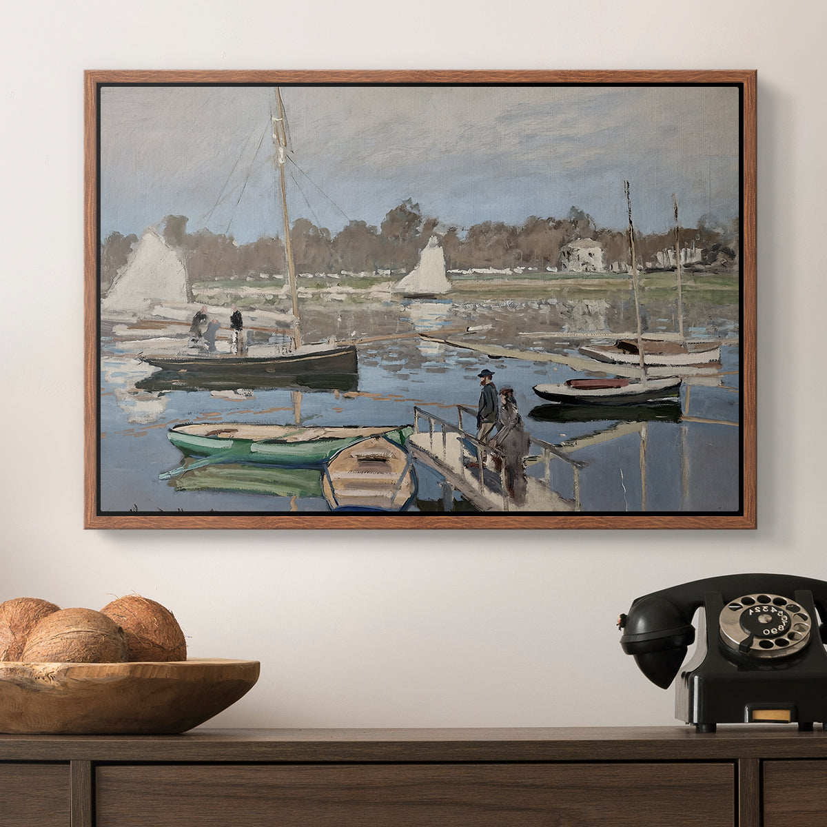 The Basin at Argenteuil, 1874 by Claude Monet in a walnut floater framed canvas displayed above a console table in a hallway, featuring a tranquil river setting with sailboats and shoreline.