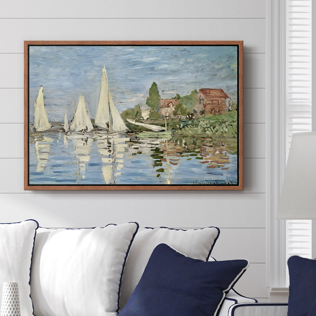 Regatta at Argenteuil, 1872 by Claude Monet displayed above a sofa in a living room in a walnut floater frame, featuring a lively regatta scene with multiple boats and fluttering sails.