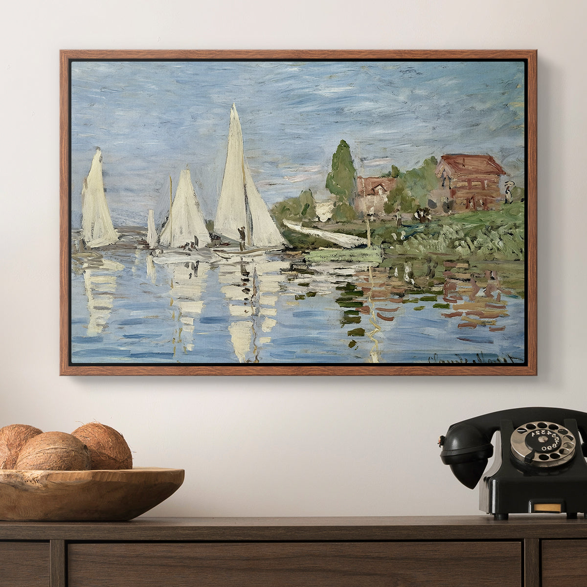 Regatta at Argenteuil, 1872 by Claude Monet in a walnut floater framed canvas displayed above a console table in a hallway, featuring a dynamic nautical scene with boats moving across river.