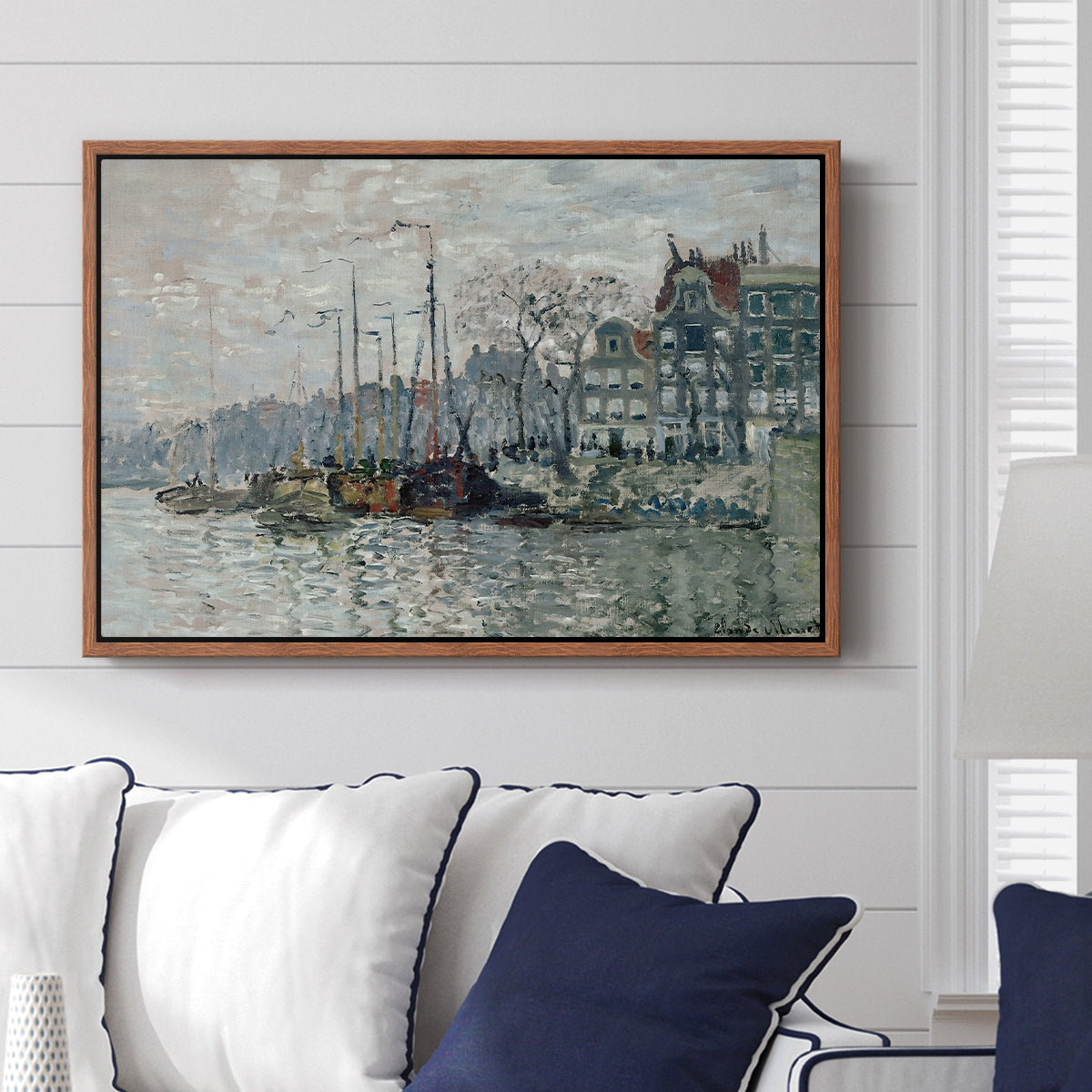 View of the Prins Hendrikkade and Kromme Waal in Amsterdam, 1874 by Claude Monet displayed above a sofa in a living room in a walnut floater frame, featuring an impressionist cityscape of canal with ships and architecture.