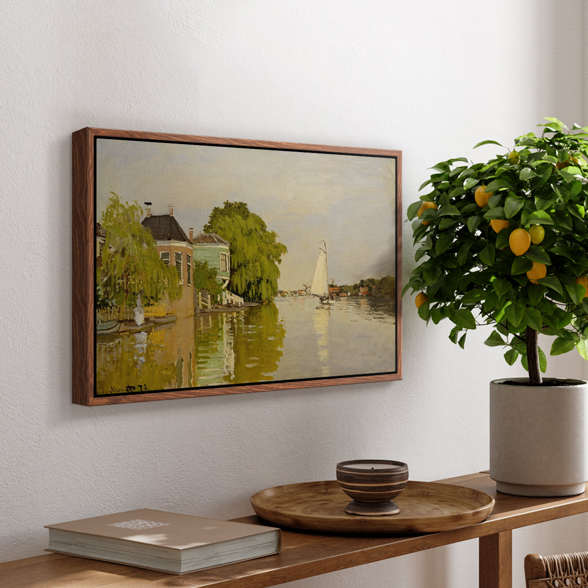Houses on the Achterzaan, 1871 by Claude Monet, presented in a walnut floater framed canvas featuring colorful houses reflected in calm river surrounded by greenery, displayed above a hallway console table.