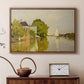 Walnut floater framed canvas featuring an impressionist landscape with buildings along quiet canal, displayed above a cabinet in a soft-toned living room.