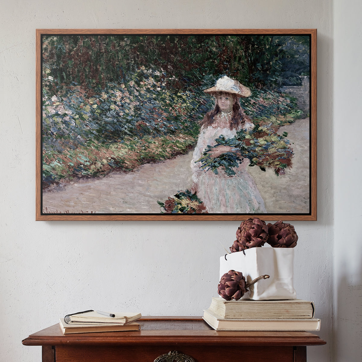 Walnut floater framed canvas featuring Young Girl in the Garden at Giverny, 1888 by Claude Monet above an entryway table in a minimalist foyer.