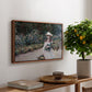 Young Girl in the Garden at Giverny, 1888 by Claude Monet, presented in a walnut floater framed canvas featuring a young girl seated in lush garden surrounded by blooming flowers, displayed above a hallway console table.