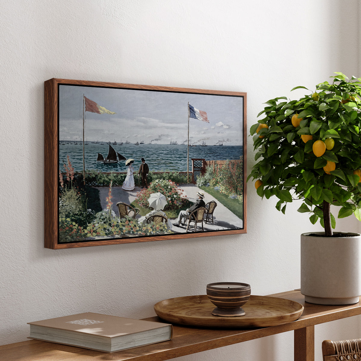 Garden at Sainte-Adresse, 1867 by Claude Monet, presented in a walnut floater framed canvas featuring a seaside garden with flowers, flags, and figures overlooking the water, displayed above a hallway console table.