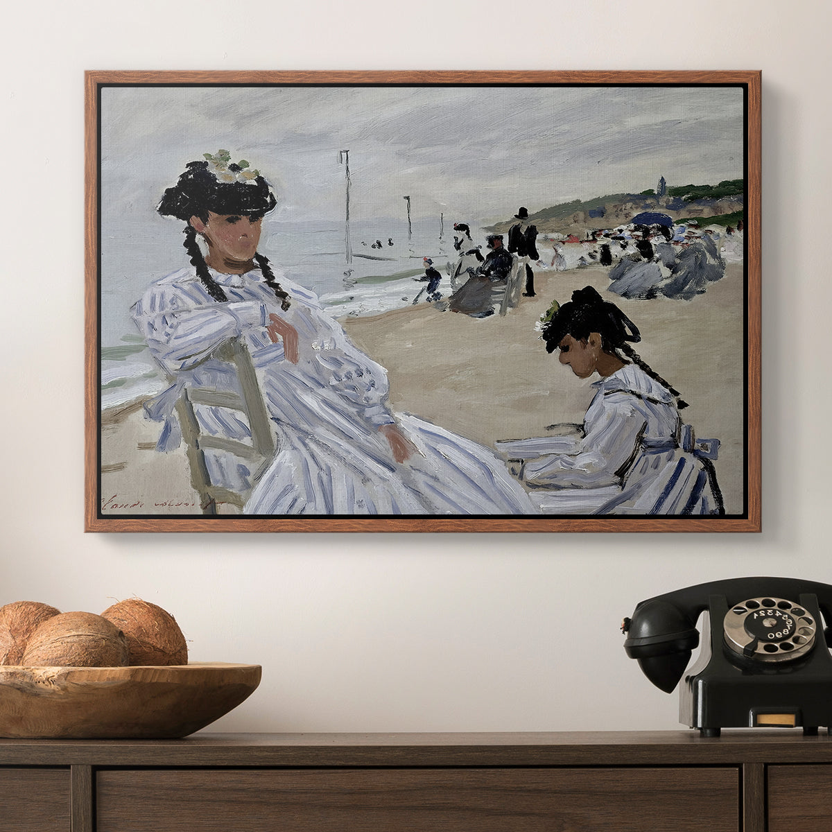 On the Beach at Trouville, 1870 by Claude Monet in a walnut floater framed canvas displayed above a console table in a hallway, featuring a coastal leisure scene with figures looking out to sea.