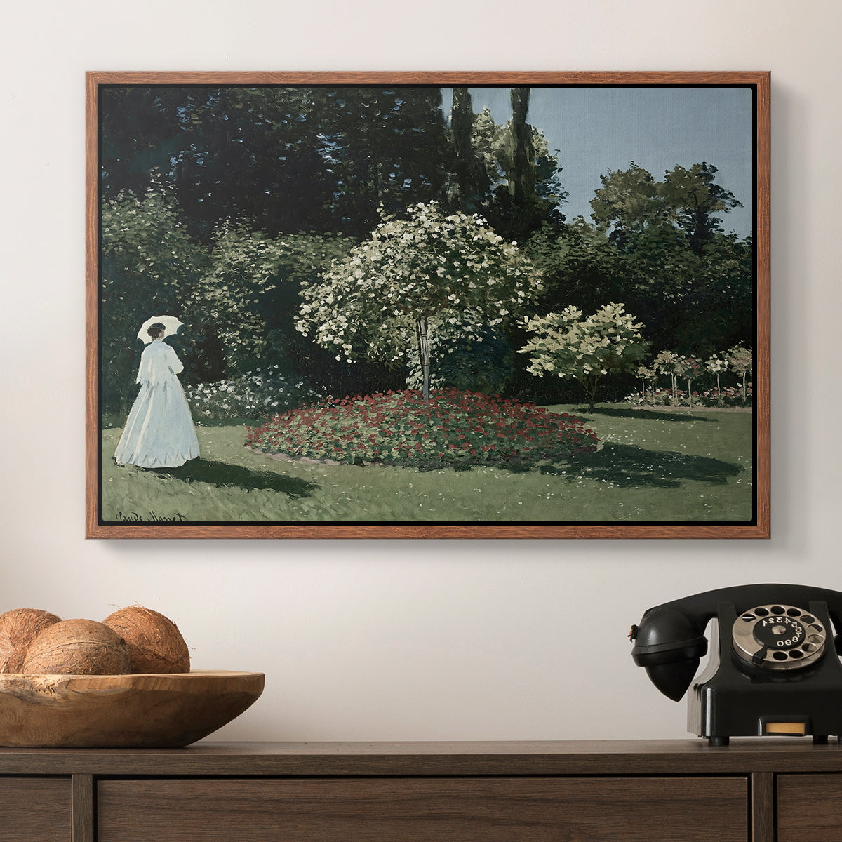 Woman in the Garden, Sainte-Adresse, 1867 by Claude Monet in a walnut floater framed canvas displayed above a console table in a hallway, featuring a tranquil garden portrait with soft natural light.