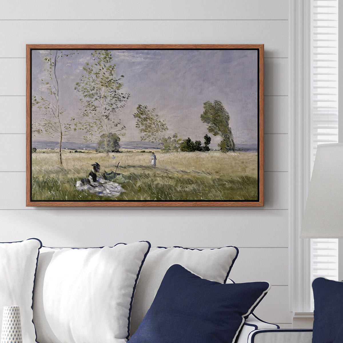 Summer (L'ete), 1874 by Claude Monet displayed above a sofa in a living room in a walnut floater frame, featuring an impressionist countryside scene with figure resting in shade.