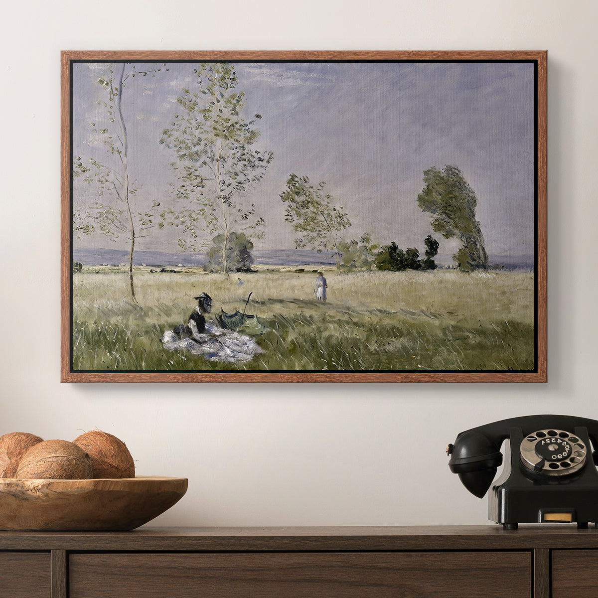 Summer (L'ete), 1874 by Claude Monet in a walnut floater framed canvas displayed above a console table in a hallway, featuring a tranquil summer landscape with lone figure in nature.
