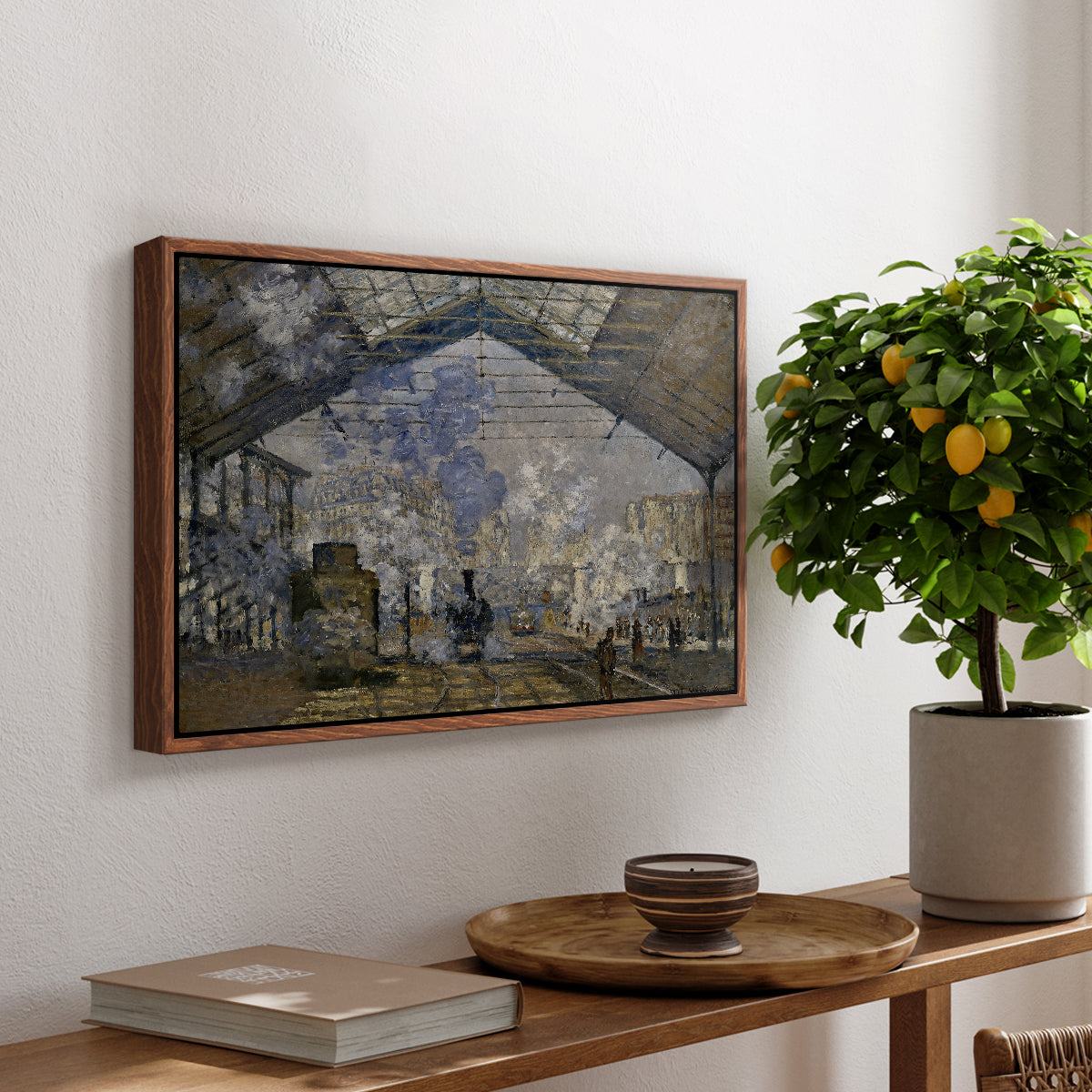 The Gare Saint-Lazare, 1877 by Claude Monet, presented in a walnut floater framed canvas featuring a train station interior filled with steam and locomotives under iron structure, displayed above a hallway console table.