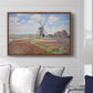 Tulip Fields with the Rijnsburg Windmill, 1886 by Claude Monet displayed above a sofa in a living room in a walnut floater frame, featuring a vibrant agricultural landscape with flowers and windmill.