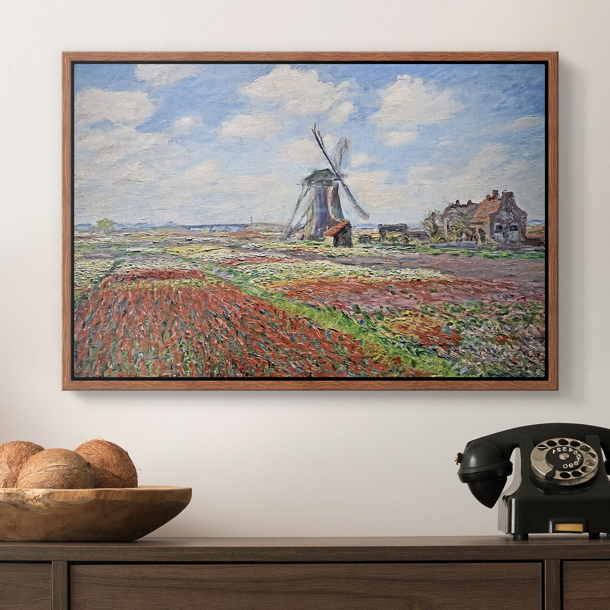 Tulip Fields with the Rijnsburg Windmill, 1886 by Claude Monet in a walnut floater framed canvas displayed above a console table in a hallway, featuring a rural scene with patterned rows of flowers and windmill.