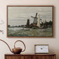 Walnut floater framed canvas featuring a rustic scene with windmill and reflections in water, displayed above a cabinet in a soft-toned living room.