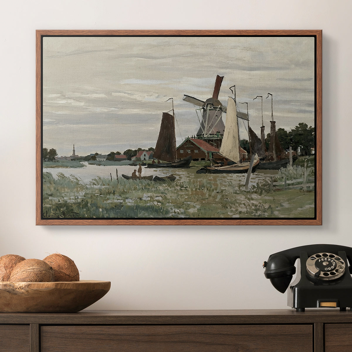 Windmill at Zaandam, 1871 by Claude Monet in a walnut floater framed canvas displayed above a console table in a hallway, featuring a countryside structure standing against open sky.