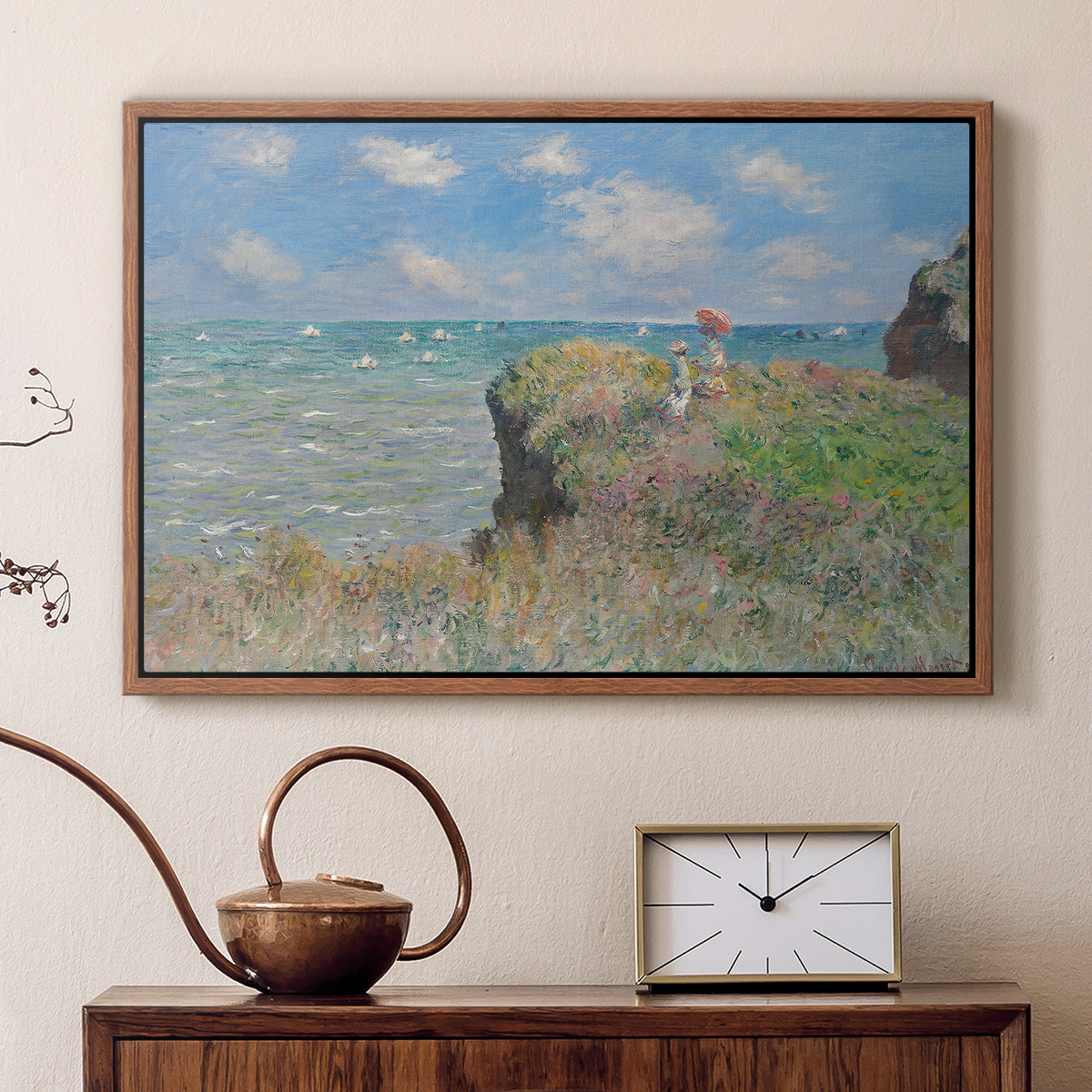 Walnut floater framed canvas featuring a coastal cliff scene with grass, wind, and expansive sea view, displayed above a cabinet in a soft-toned living room.
