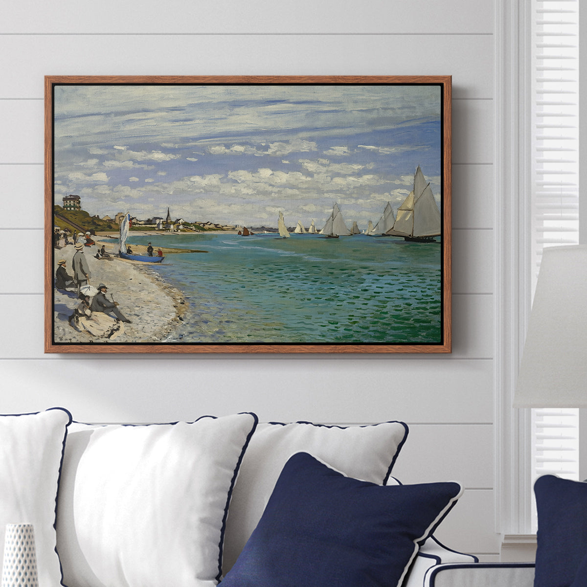 Regatta at Sainte-Adresse, 1867 by Claude Monet displayed above a sofa in a living room in a walnut floater frame, featuring a lively regatta scene with boats and people on beach.