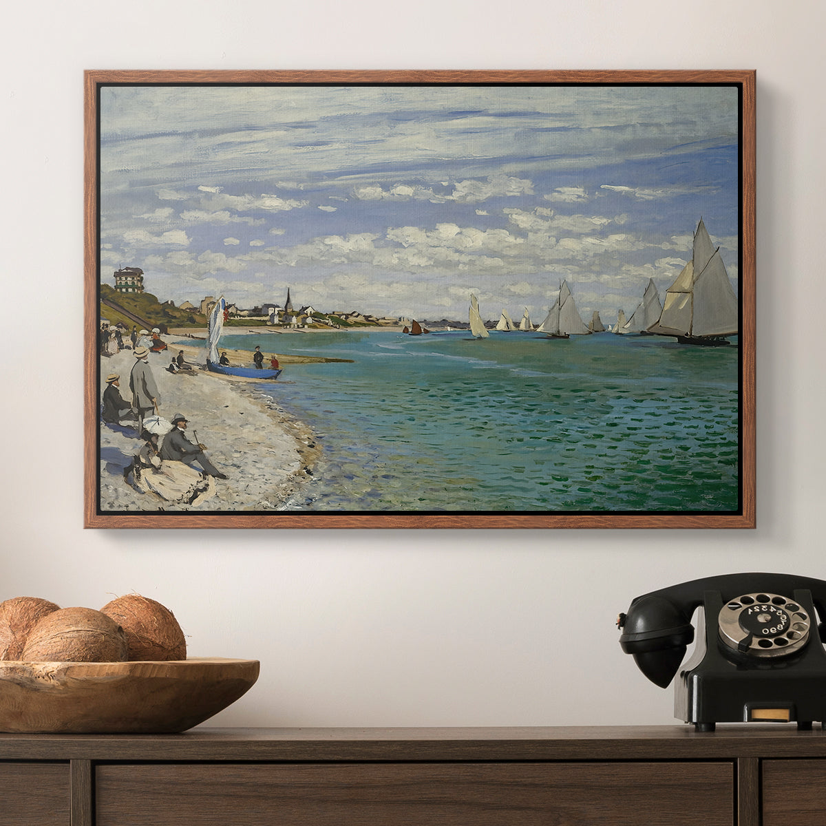 Regatta at Sainte-Adresse, 1867 by Claude Monet in a walnut floater framed canvas displayed above a console table in a hallway, featuring a nautical scene with boats racing near seaside town.