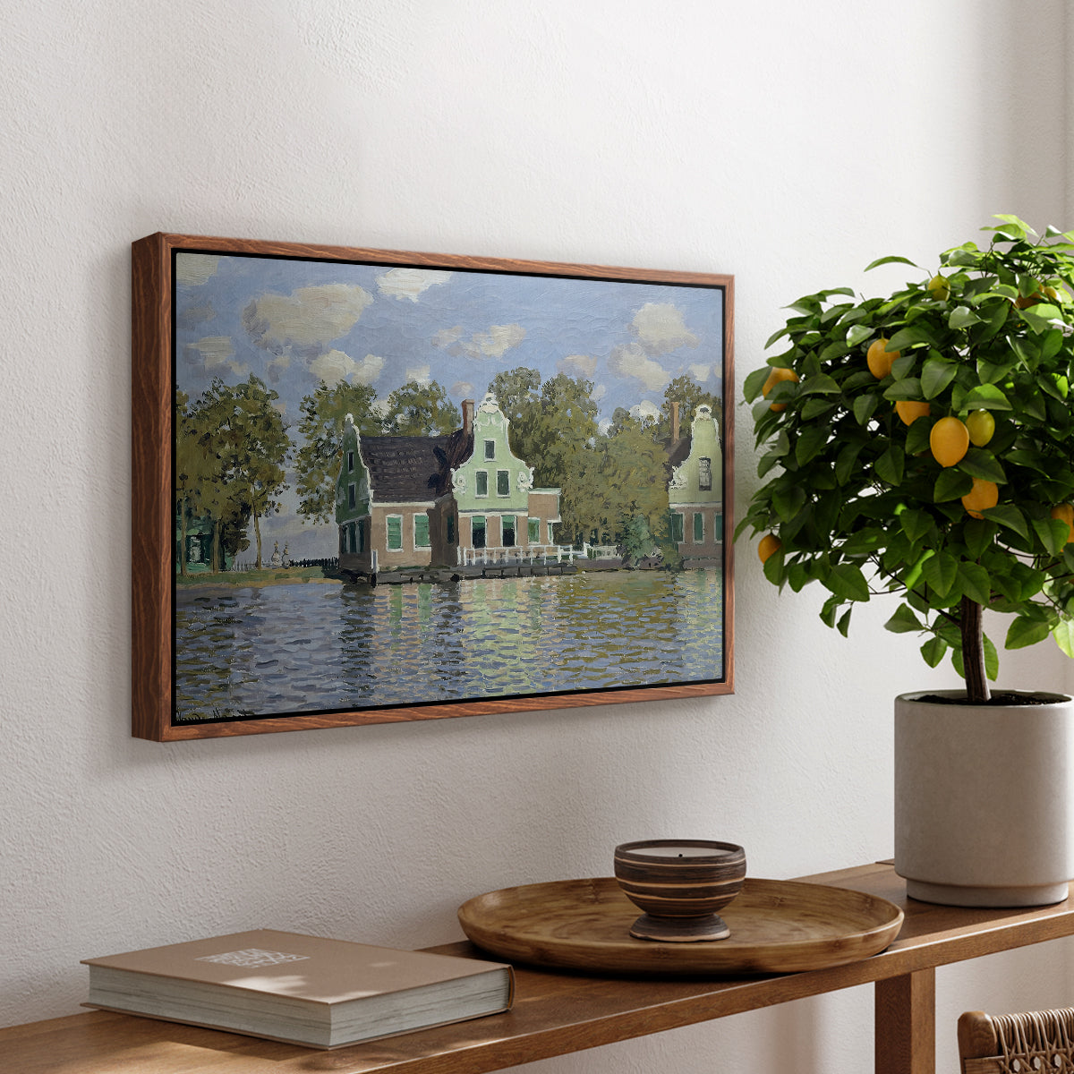 Houses on the Zaan River at Zaandam, 1871 by Claude Monet, presented in a walnut floater framed canvas featuring a row of houses along river with reflections in calm water, displayed above a hallway console table.