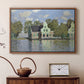 Walnut floater framed canvas featuring a peaceful canal scene with houses mirrored in water, displayed above a cabinet in a soft-toned living room.