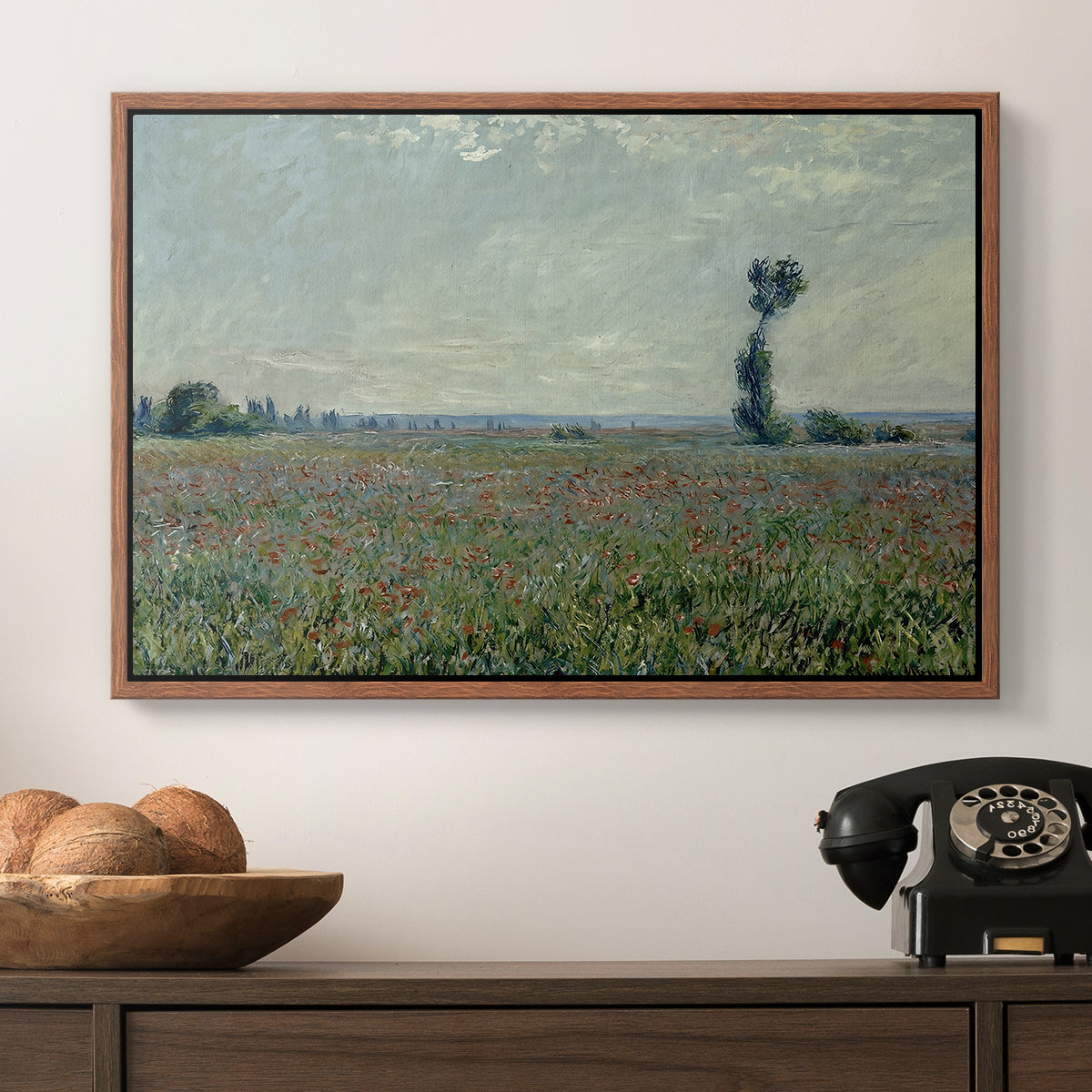 Poppy Field, 1881 by Claude Monet in a walnut floater framed canvas displayed above a console table in a hallway, featuring a natural field scene with vibrant red flowers.
