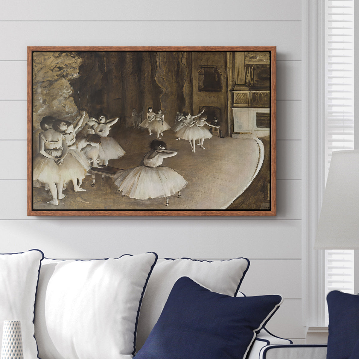 The Rehearsal of the Ballet Onstage, 1874 by Edgar Degas displayed above a sofa in a living room in a walnut floater frame, featuring a stage rehearsal scene with dancers preparing performance.