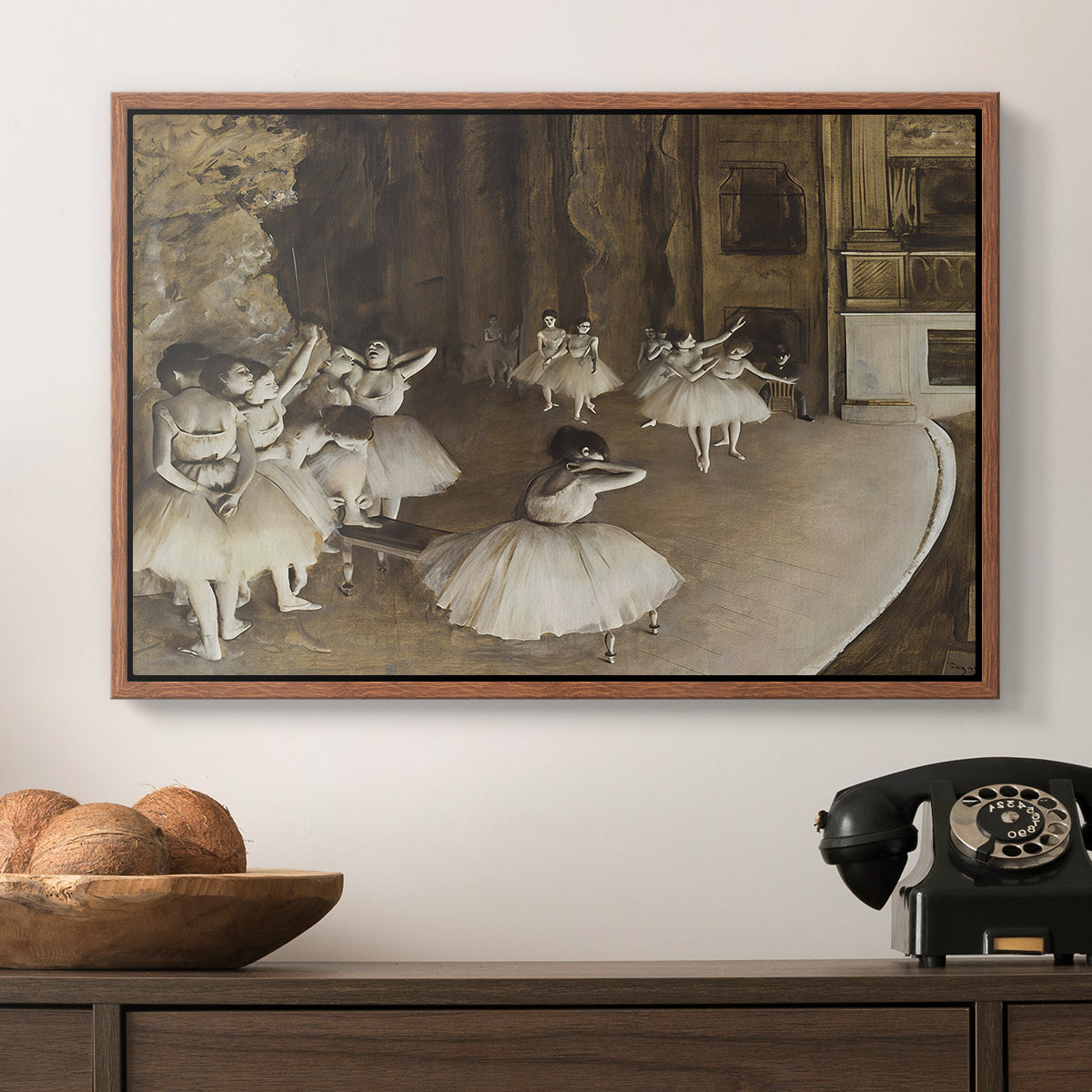The Rehearsal of the Ballet Onstage, 1874 by Edgar Degas in a walnut floater framed canvas displayed above a console table in a hallway, featuring dancers arranged on stage with visible set and depth.
