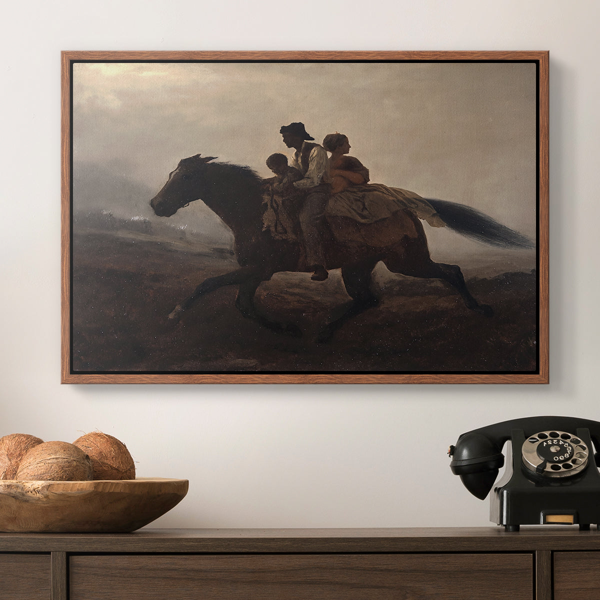A Ride for Liberty – The Fugitive Slaves, c. 1862 by Eastman Johnson in a walnut floater framed canvas displayed above a console table in a hallway, featuring figures on horse moving swiftly through shadowy landscape.