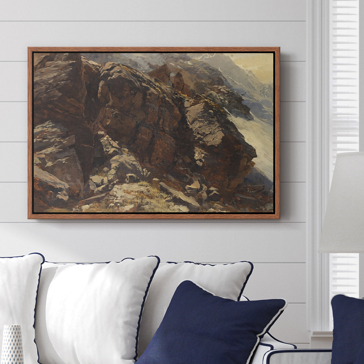 High Mountain Study, c. 1870 by Edward Theodore Compton displayed above a sofa in a living room in a walnut floater frame, featuring a detailed study of rugged mountain landscape with sharp contours.