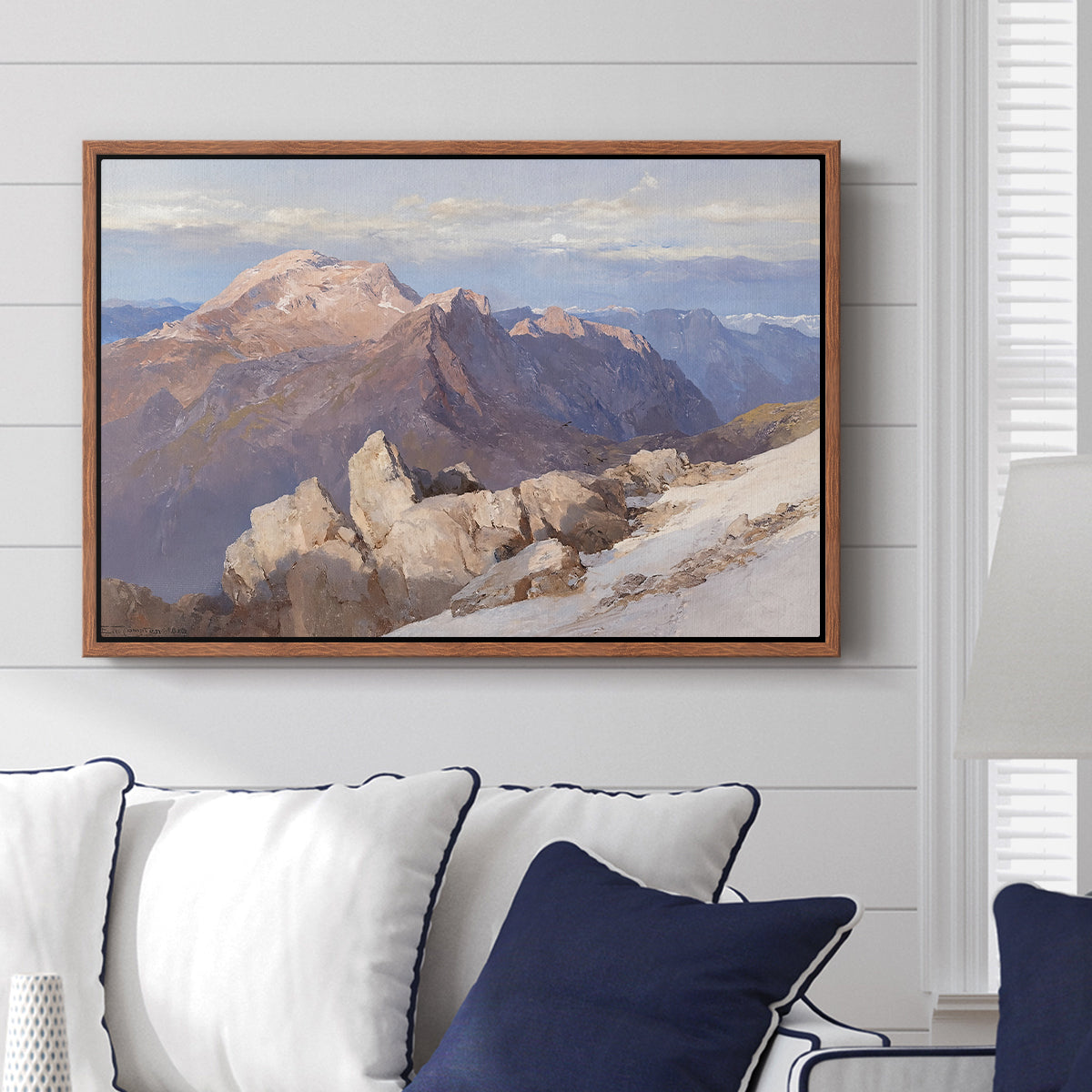 Hoher Göll from Watzmann-Hocheck, 1919 by Edward Theodore Compton displayed above a sofa in a living room in a walnut floater frame, featuring an alpine panorama showing layered peaks and valleys.