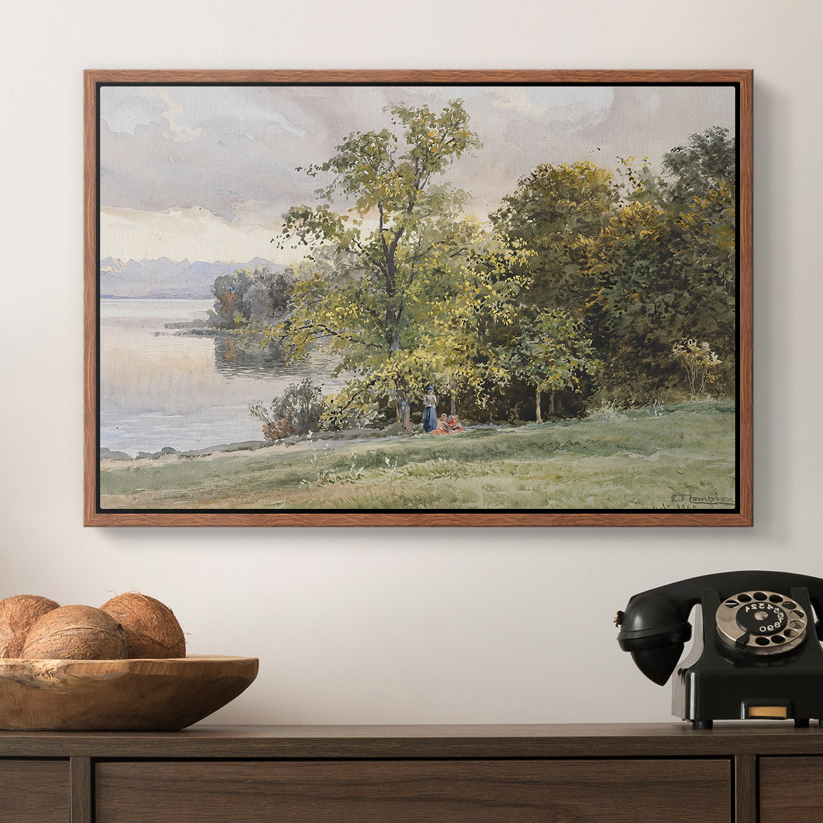 Landscape at Lake Starnberg, 1890 by Edward Theodore Compton in a walnut floater framed canvas displayed above a console table in a hallway, featuring a tranquil lakeside view with soft atmospheric tones.