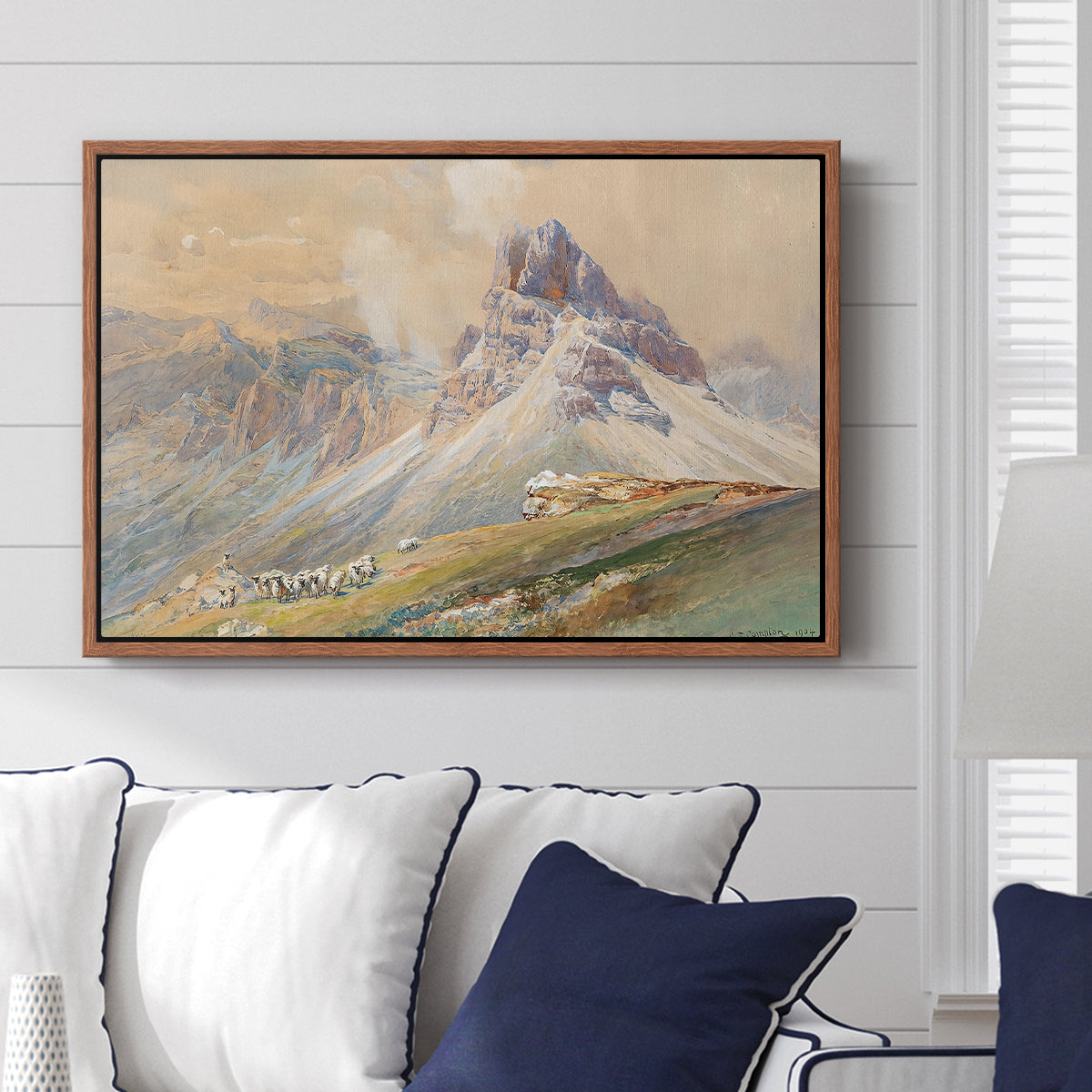 From the Dolomites, 1904 by Edward Theodore Compton displayed above a sofa in a living room in a walnut floater frame, featuring an alpine scene with jagged rock formations and distant mountains.