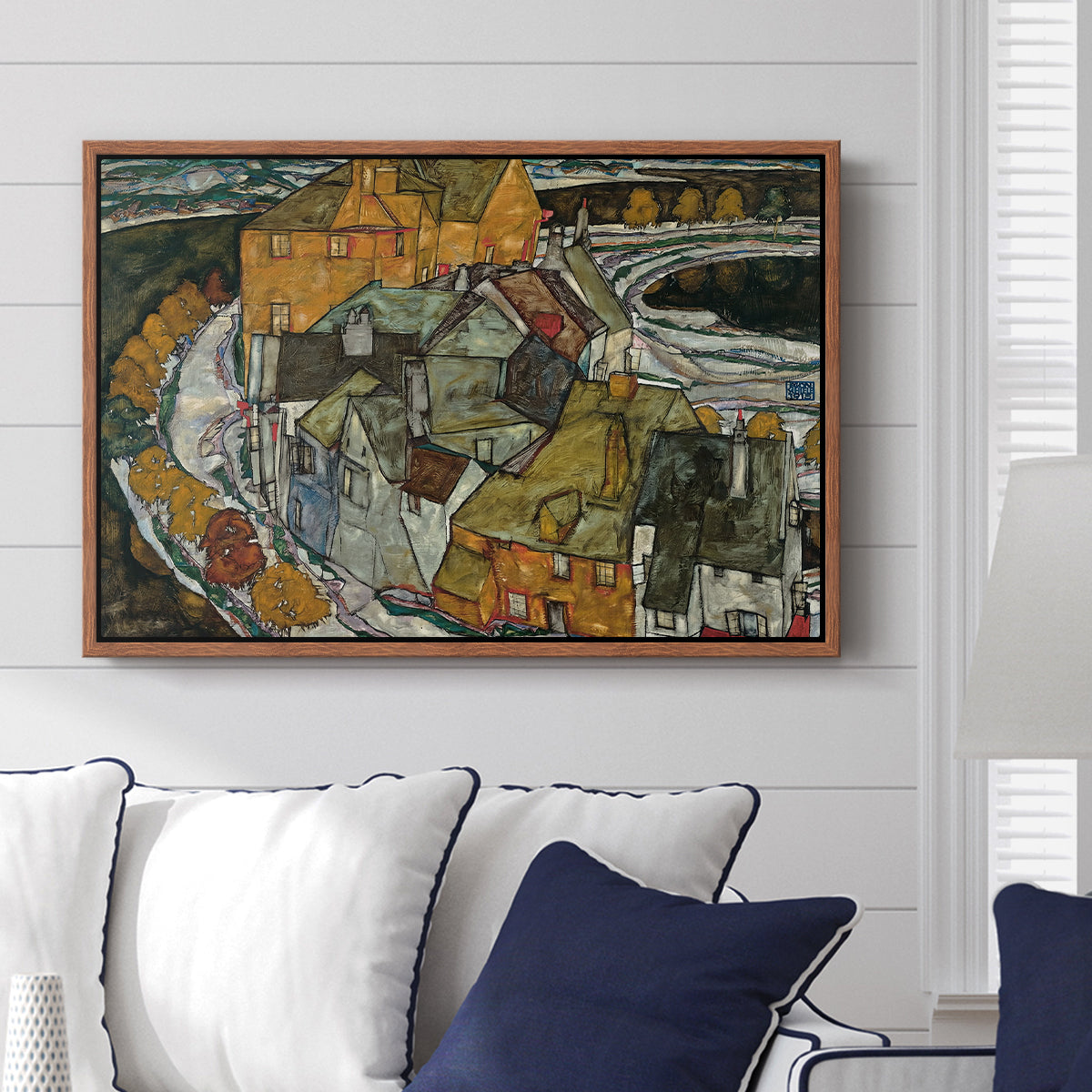 Crescent of Houses II (Island Town), 1915 by Egon Schiele displayed above a sofa in a living room in a walnut floater frame, featuring a stylized townscape with clustered buildings and bold outlines.