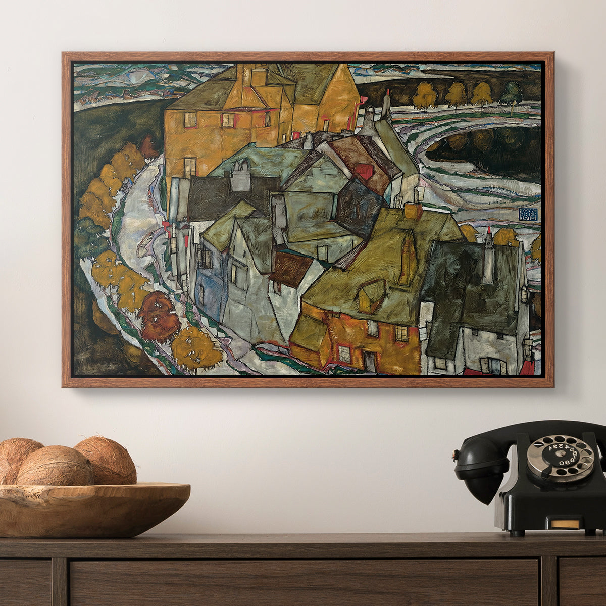 Crescent of Houses II (Island Town), 1915 by Egon Schiele in a walnut floater framed canvas displayed above a console table in a hallway, featuring an architectural scene with houses arranged in curved composition.