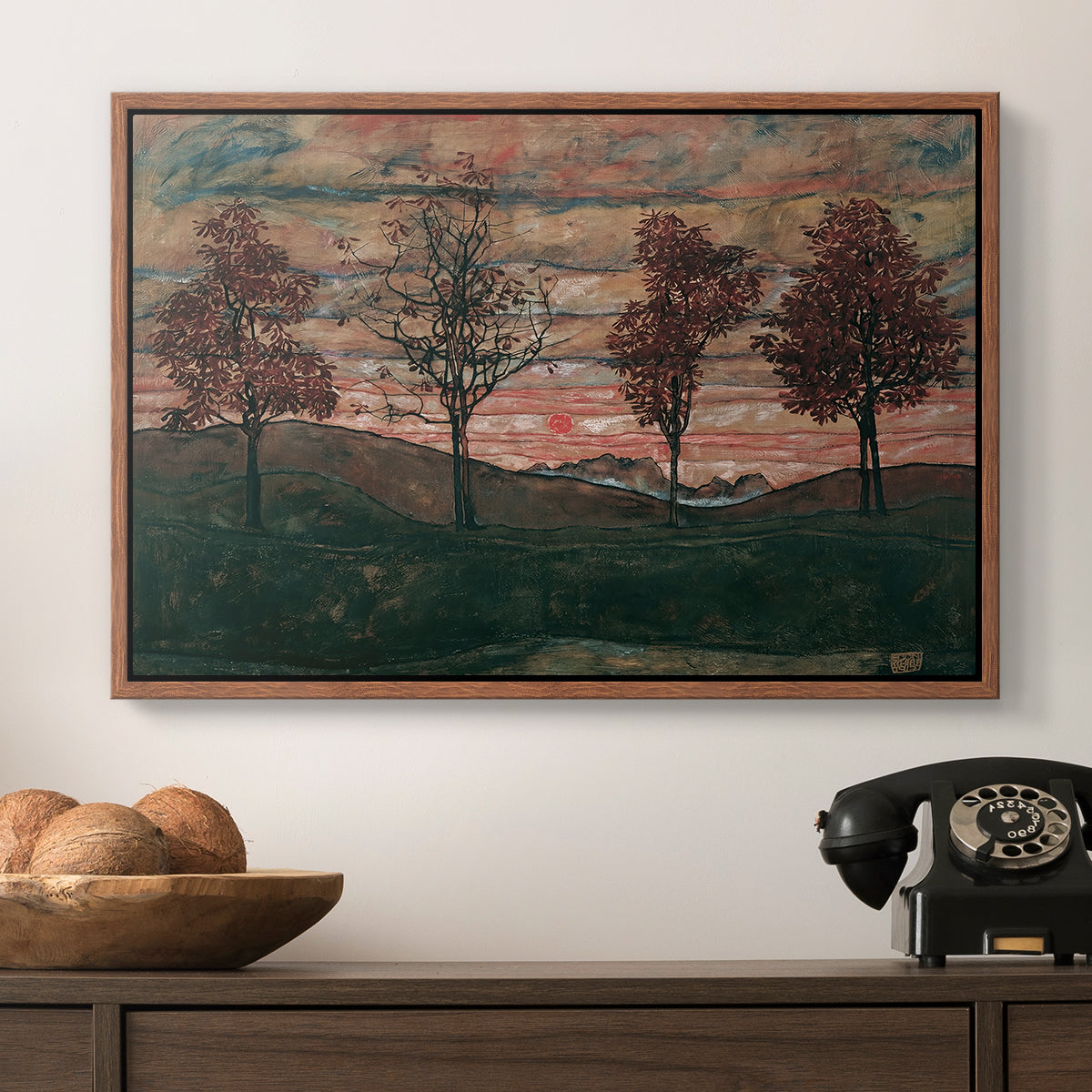 Four Trees, 1917 by Egon Schiele in a walnut floater framed canvas displayed above a console table in a hallway, featuring an expressionist landscape featuring isolated trees in field.